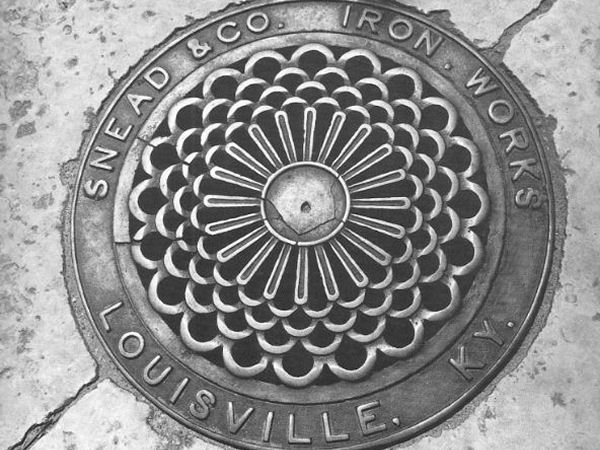 Close up of a sewer grate that reads "Snead & Co Iron Works Louisville KY"