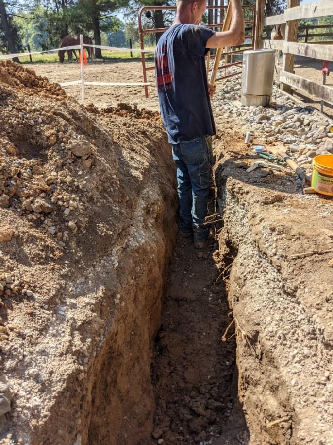 Tom Sondergeld Plumbing employee standing in a dirt trench