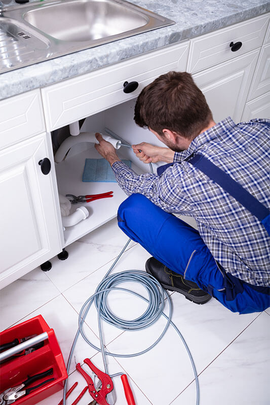 Plumber snaking a kitchen sink drain